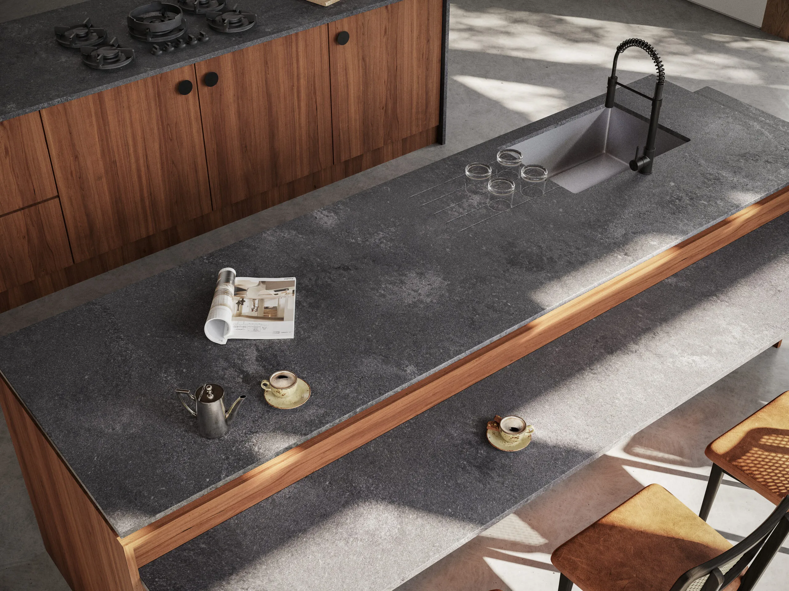 Dark Caesarstone kitchen countertop with drainer grooves next to a stainless steel sink, complemented by wood cabinets and natural lighting.